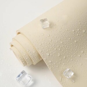 May include: A close-up of a rolled up off-white yoga mat with water droplets on the surface. Three clear ice cubes are scattered around the mat.