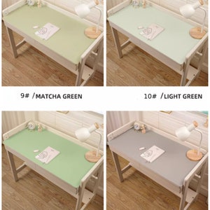 May include: Four different colored desk mats on a white desk with a lamp and a book. The colors are matcha green, light green, lake green, and grey.