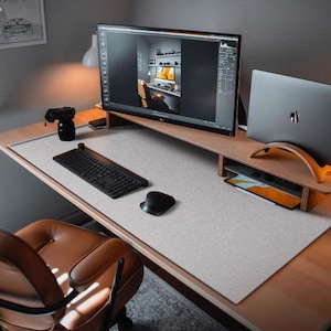 May include: A modern home office desk setup with a large curved monitor, a laptop, a keyboard, a mouse, and a brown leather office chair. The desk has a light grey textured desk mat.