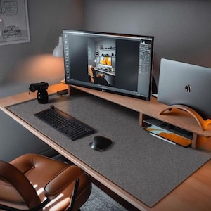 May include: A grey desk mat with a textured surface. A black keyboard, a black mouse, and a black camera are on the desk mat. A computer monitor and a laptop are on the desk.