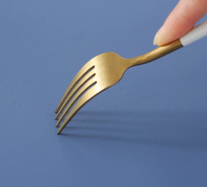May include: A gold fork with a white handle on a blue background.