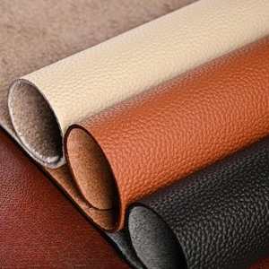 Puede incluir: Cuatro rollos de cuero en diferentes colores: marrón, beige, naranja y negro. El cuero tiene una superficie texturizada.