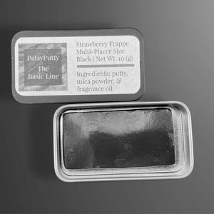 May include: A black putty product in a silver tin. The tin is open, revealing the product inside. The label reads "PatsyPutty The Basic Line" and lists the product as "Strawberry Frappe Multi-Placer Size Black Net Wt. 10 (g)". Ingredients include putty, mica powder, and fragrance oil.