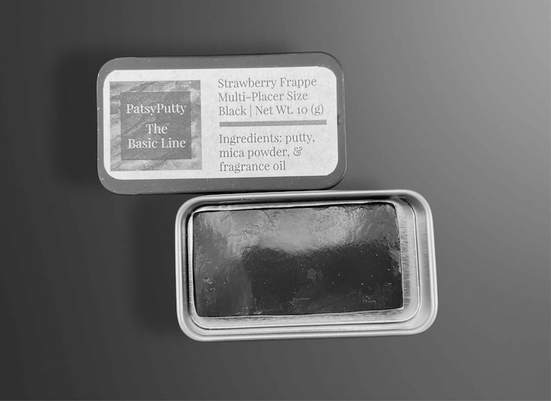 May include: A black putty product in a silver tin. The tin is open, revealing the product inside. The label reads "PatsyPutty The Basic Line" and lists the product as "Strawberry Frappe Multi-Placer Size Black Net Wt. 10 (g)". Ingredients include putty, mica powder, and fragrance oil.