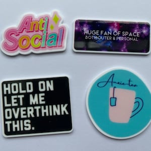 Könnte beinhalten: Vier bunte Aufkleber mit Text. Einer sagt "Anti Social" in Rosa und Gelb. Ein anderer sagt "HUGE FAN OF SPACE BOTH OUTER & PERSONAL" mit einem Galaxienhintergrund. Ein dritter sagt "HOLD ON LET ME OVERTHINK THIS." Der letzte sagt "Anxie tea" mit einer Tasse.