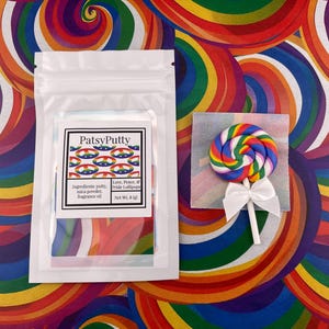 Könnte beinhalten: Ein weißer Beutel mit dem Etikett "PatsyPutty" und ein Regenbogen-Lutscher. Das Etikett listet Zutaten und "Love, Peace, & Pride Lollipops" auf. Der Lutscher ist ein Wirbel aus Regenbogenfarben mit einer weißen Schleife.