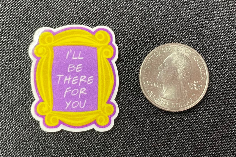 Pu&ograve; includere: Un adesivo a tema della serie TV Friends, con l'iconica cornice gialla con la scritta "I'll Be There For You" in bianco su sfondo viola. Accanto c'&egrave; una moneta.
