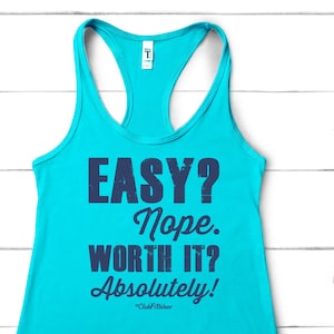 May include: A turquoise tank top with the text "EASY? Nope. WORTH IT? Absolutely!" printed in dark blue. The text is in a distressed font style.