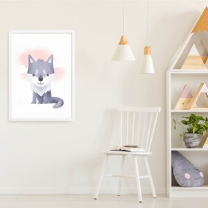 May include: A white framed print of a cartoon wolf with a pink and white background. The wolf is sitting down and looking at the viewer. The print is hanging on a white wall.