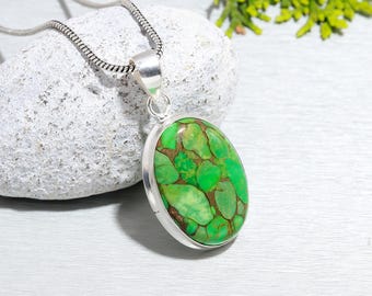 Puede incluir: Un collar de cadena de plata con un colgante ovalado verde con una piedra verde y marrón. El colgante está engastado en un bisel de plata.