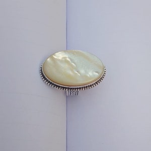 Peut inclure: Une bague en argent avec une grande pierre ovale en nacre.