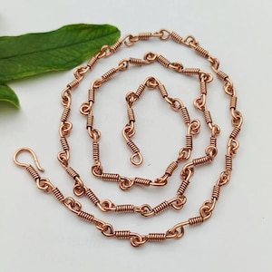 May include: A copper chain necklace with a coiled wire design. The chain is approximately 20 inches long and has a lobster clasp closure.