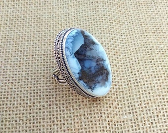 May include: A silver ring with an oval-shaped, white and gray gemstone. The gemstone has a unique pattern of gray and black inclusions. The ring has a detailed, ornate silver band.