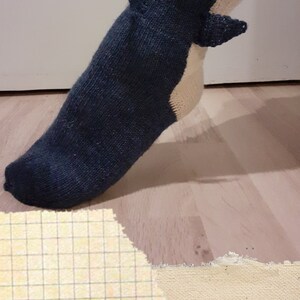 Könnte beinhalten: Eine blaue und weiße gestrickte Socke mit einem Hai-Design. Die Socke wird an einem Fuß getragen. Der Text "Digital Pattern" ist am unteren Rand des Bildes sichtbar.