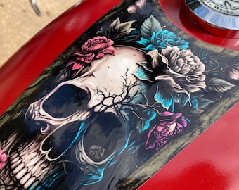 May include: A black and white skull with a tree growing out of it, surrounded by pink, blue, and white flowers. The skull is on a red background.