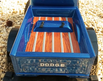 May include: A blue pickup truck bed with a wooden bed liner and the word "DODGE" in silver lettering on the back.