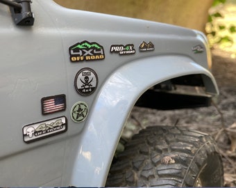 May include: A gray truck with several stickers on the side. The stickers include "4x4 Off Road", "Pro 4x Off Road", "Trail Rated", "Pirate Rated 4x4", and a skull and crossbones.