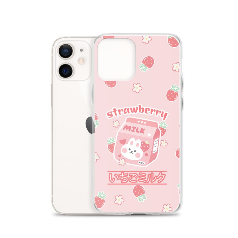 May include: A pink phone case with a cartoon bunny holding a carton of strawberry milk. The carton says "Strawberry Milk" and "いちごミルク" in Japanese. The case is decorated with strawberries and flowers.