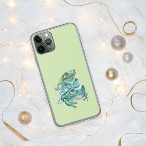May include: A clear phone case with a green, blue and white illustration of three frogs stacked on top of each other.