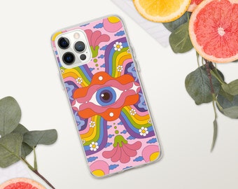 Puede incluir: Una funda de iPhone rosa con un diseño psicodélico que presenta un arcoíris, flores y un ojo grande. La funda es transparente y muestra el objetivo de la cámara del teléfono.