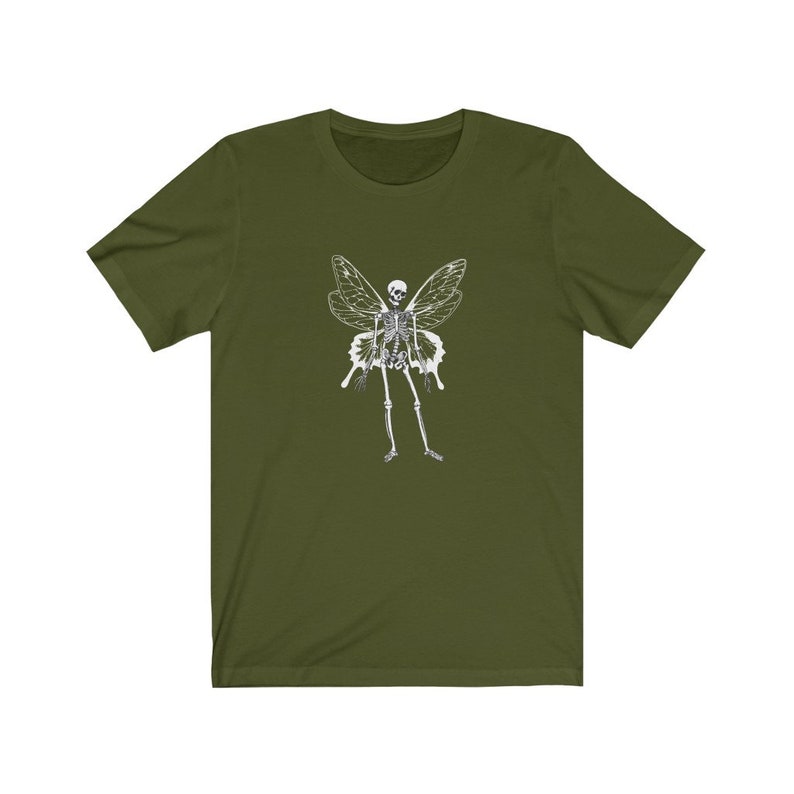 Puede incluir: Una camiseta verde con un gr&aacute;fico de hada esqueleto blanco. El hada tiene alas y est&aacute; de pie con los brazos a los lados.