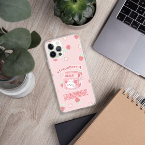 May include: A pink phone case with a cartoon strawberry milk carton and the text "strawberry" and "いちごミルク". The case is decorated with small white flowers and red strawberries.