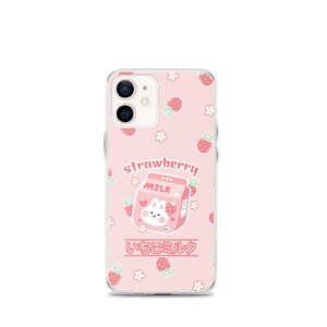 May include: A pink phone case with a cartoon strawberry milk carton and a bunny. The case has a white background with pink strawberries and flowers. The text "strawberry milk" and "いちごミルク" is printed on the case.