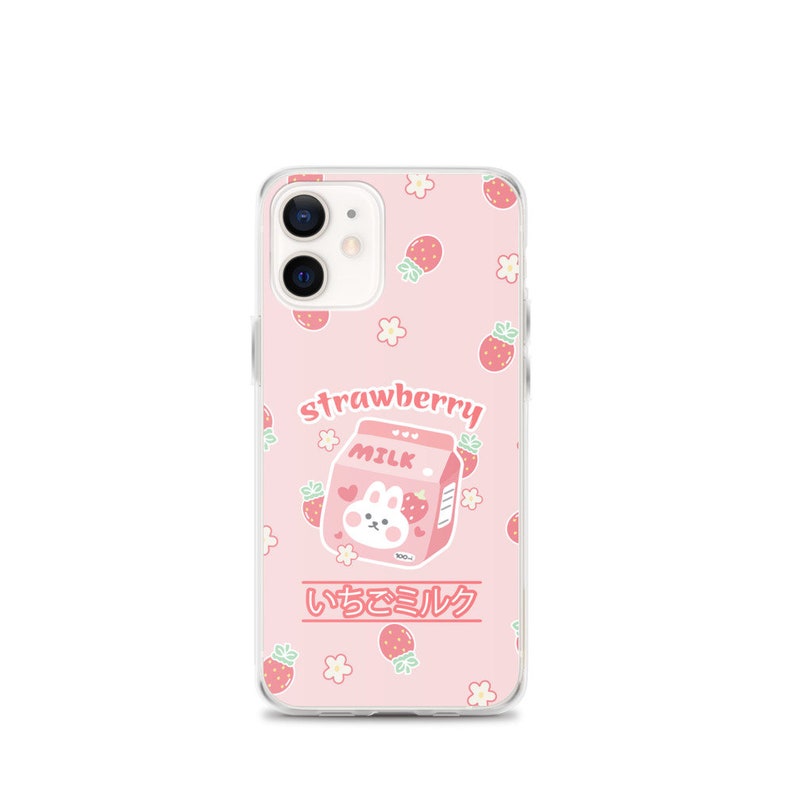 May include: A pink phone case with a cartoon strawberry milk carton and a bunny. The case has a white background with pink strawberries and flowers. The text "strawberry milk" and "いちごミルク" is printed on the case.