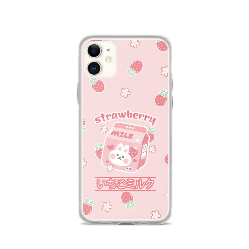 May include: A pink and white phone case with a cartoon bunny holding a carton of strawberry milk. The carton says "Strawberry Milk" and "いちごミルク". The case is decorated with strawberries and flowers.