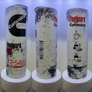 May include: A white and black insulated tumbler with a distressed look. The tumbler features the Cummins logo and the text "Fleetguard" and "FF5488".