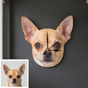 May include: A wall clock shaped like the head of a tan Chihuahua dog with large upright ears and dark brown eyes. The clock face features a high-resolution print of the dog's face with black hour, minute, and second hands centred on the nose.
