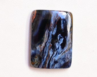 May include: A blue and black gemstone with a swirling pattern. The gemstone is rectangular and has a smooth, polished surface.
