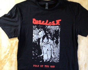 May include: Black t-shirt with a white graphic print of a person and the text "DISCLOSE FEAR OF THE WAR" in red.