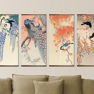 May include: Four framed Japanese-style prints featuring birds and flowers. The prints are on a light background with a brown frame. The first print features a blue and white bird on a branch with purple wisteria flowers. The second print features a peacock with blue and green feathers on a branch with a light pink background. The third print features a blue bird on a branch with orange leaves. The fourth print features a black and white bird on a branch with orange and white flowers.