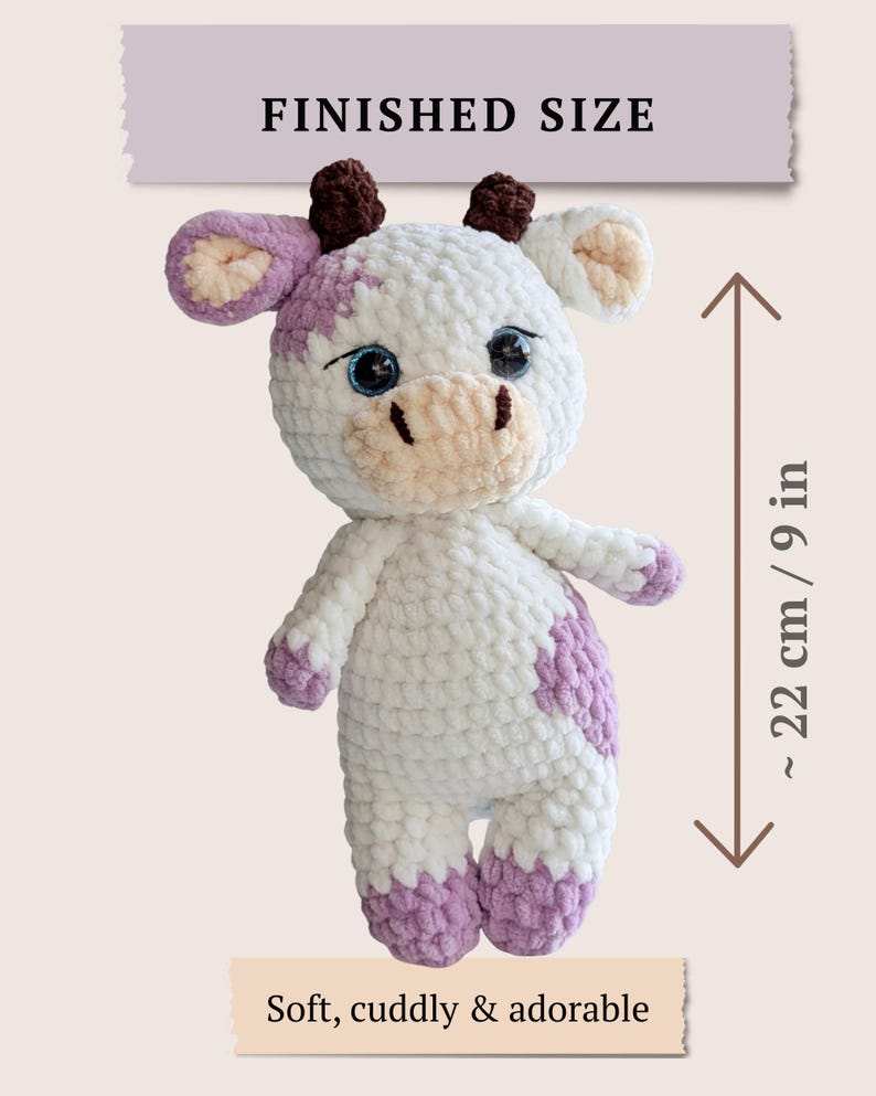 May include: A white and lavender crocheted cow plush toy with dark brown horns, large blue eyes, and a light beige muzzle. The toy features a finished size of approximately 9 inches, as indicated by the text and measurement graphic.