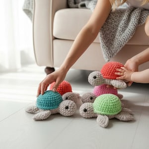 May include: A collection of four small, handmade crochet turtles with light gray bodies and textured shells in vibrant colors including teal, coral, pink, and lime green. Each turtle features black bead eyes and a soft, plush yarn construction.