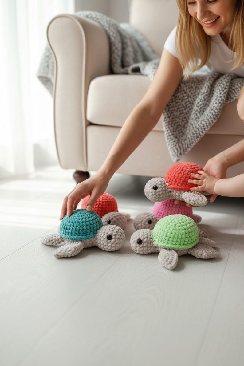 May include: A collection of four small, handmade crochet turtles with light gray bodies and textured shells in vibrant colors including teal, coral, pink, and lime green. Each turtle features black bead eyes and a soft, plush yarn construction.
