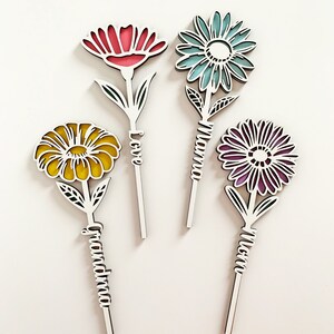 May include: Four wooden flower cutouts with different colored flowers and the words "Love", "Grandma", "Mom", and "Mama" written on the stems.