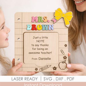 Könnte beinhalten: Lehrer-Dankestafel aus Holz mit den Worten "MRS. BROWN" in bunten Buchstaben. Die Tafel enthält eine Notiz mit der Aufschrift "Nur eine kleine NOTE, um Danke zu sagen, dass Sie eine tolle Lehrerin sind!" und ist mit einer gelben Schleife und einem Bleistift verziert.