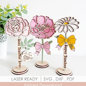 Puede incluir: Tres decoraciones de flores de madera para profesores. Cada flor tiene un diseño diferente, con pétalos rosas y blancos. Una tiene un lazo y otra un lápiz. El texto dice "Best Teacher Ever" y "Super Teacher".