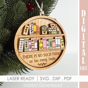 May include: Wooden Christmas ornament with a bookshelf design. The ornament features a two-tiered shelf with colorful, laser-cut books, a cactus, and a teacup. The text "THERE IS NO SUCH THING as too many books" is engraved on the bottom shelf.