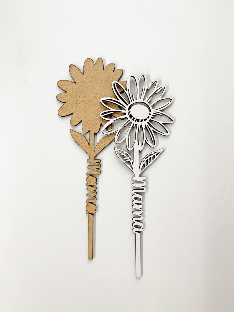 May include: Two wooden flower cutouts, one brown and one white. The white flower has the word "Mama" written on the stem.