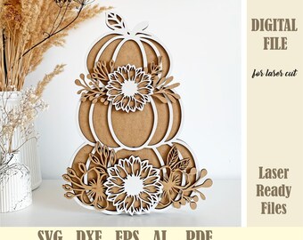 May include: A layered pumpkin decoration with white and brown details. The pumpkins are decorated with white flowers and leaves. The image includes the text: '.SVG .DXF .EPS .AI .PDF' and 'DIGITAL FILE for laser cut'.