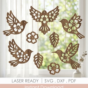 May include: Wooden bird and floral hanging decorations. The birds and flowers are laser cut with intricate details. The decorations are suspended by strings. The text "LASER READY | SVG . DXF . PDF Instant Download" is at the bottom.