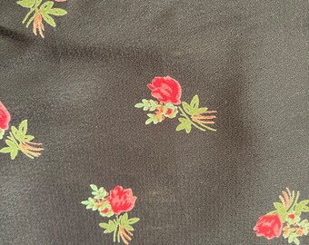 May include: Black fabric with a repeating pattern of small red roses and green leaves.