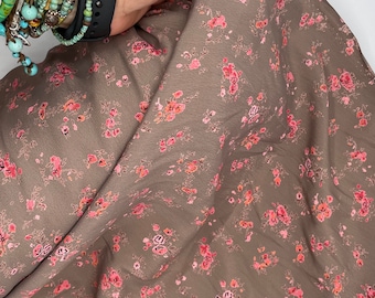 May include: A close-up of a brown fabric with a small pink floral pattern. The fabric is soft and has a subtle sheen.