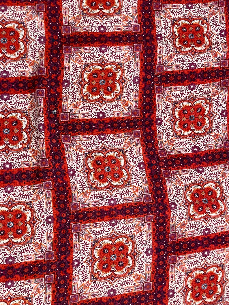 K&ouml;nnte beinhalten: Roter, wei&szlig;er und burgunderfarbener Stoff mit einem sich wiederholenden geometrischen Muster. Der Stoff hat ein paisleyartiges Muster.