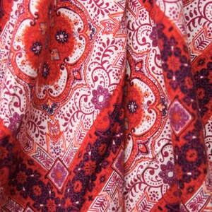 K&ouml;nnte beinhalten: Roter und wei&szlig;er Stoff mit Paisley-Muster. Der Stoff hat eine strukturierte Oberfl&auml;che und ist so gefaltet, dass das Muster sichtbar ist.