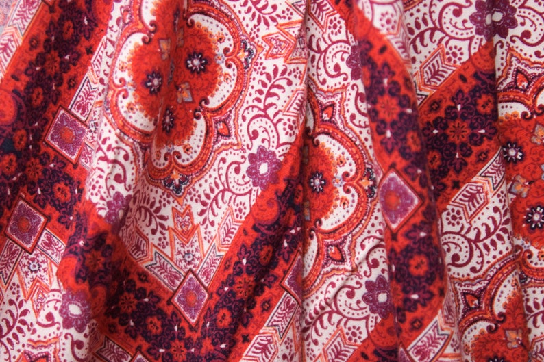 K&ouml;nnte beinhalten: Roter und wei&szlig;er Stoff mit Paisley-Muster. Der Stoff hat eine strukturierte Oberfl&auml;che und ist so gefaltet, dass das Muster sichtbar ist.