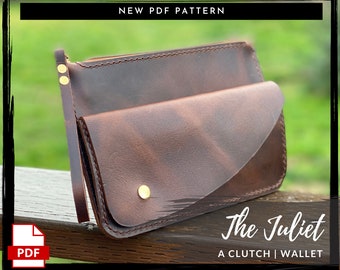 Peut inclure: Un portefeuille-pochette en cuir marron avec une fermeture à rabat et une dragonne. Le portefeuille est intitulé "The Juliet A Clutch | Wallet".